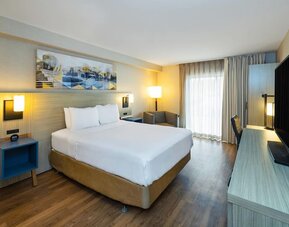 Bright king guest room with workspace, flat-screen TV, and cozy seating area at Comfort Inn Sydney.