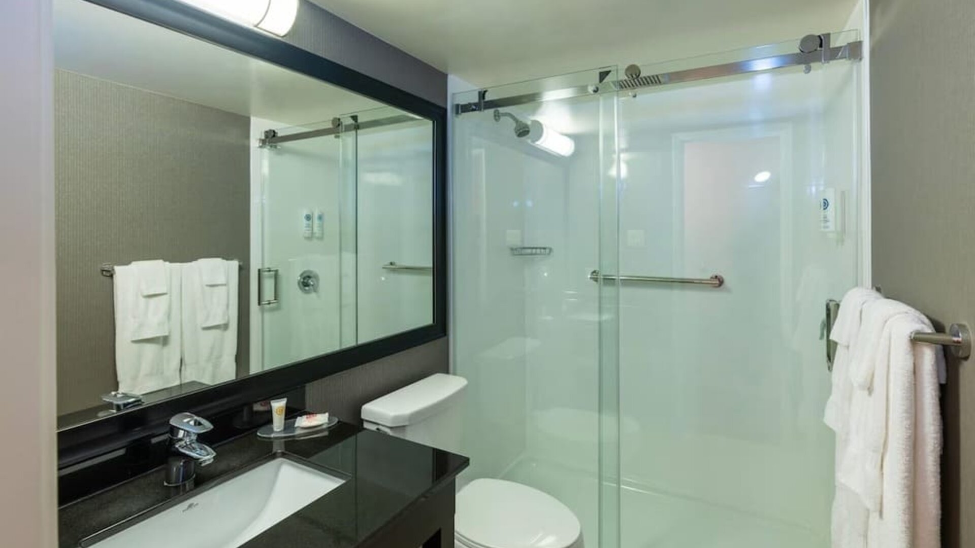 Modern guest bathroom featuring a spacious walk-in shower, sleek vanity, and complimentary bath amenities at Comfort Inn Sydney.