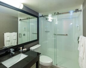 Modern guest bathroom featuring a spacious walk-in shower, sleek vanity, and complimentary bath amenities at Comfort Inn Sydney.