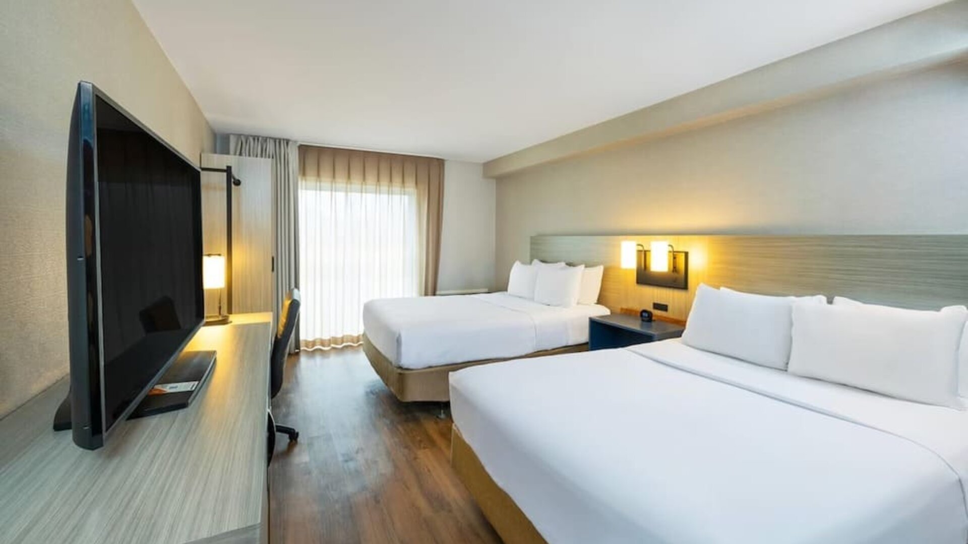 Spacious guest room with two queen beds, large TV, and comfortable work area at Comfort Inn Sydney.