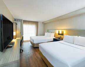 Spacious guest room with two queen beds, large TV, and comfortable work area at Comfort Inn Sydney.