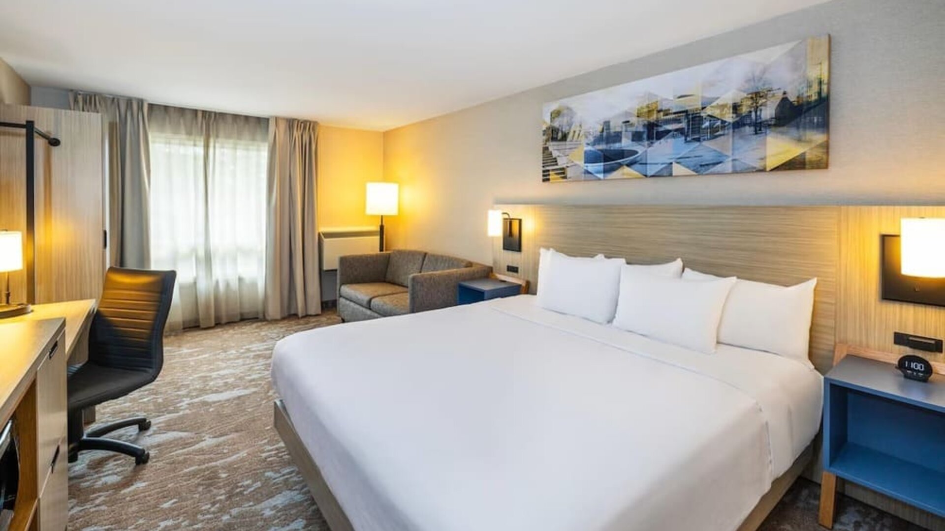 Spacious king guest room with sofa seating, work desk, and modern furnishings at Comfort Inn Sydney.