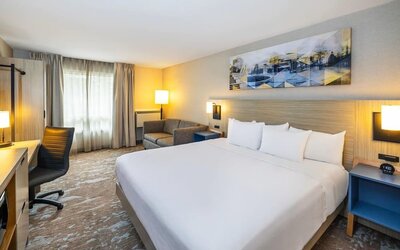 Spacious king guest room with sofa seating, work desk, and modern furnishings at Comfort Inn Sydney.