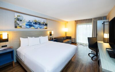Comfortable king guest room featuring a bright workspace, sofa, and large flat-screen TV at Comfort Inn Sydney.