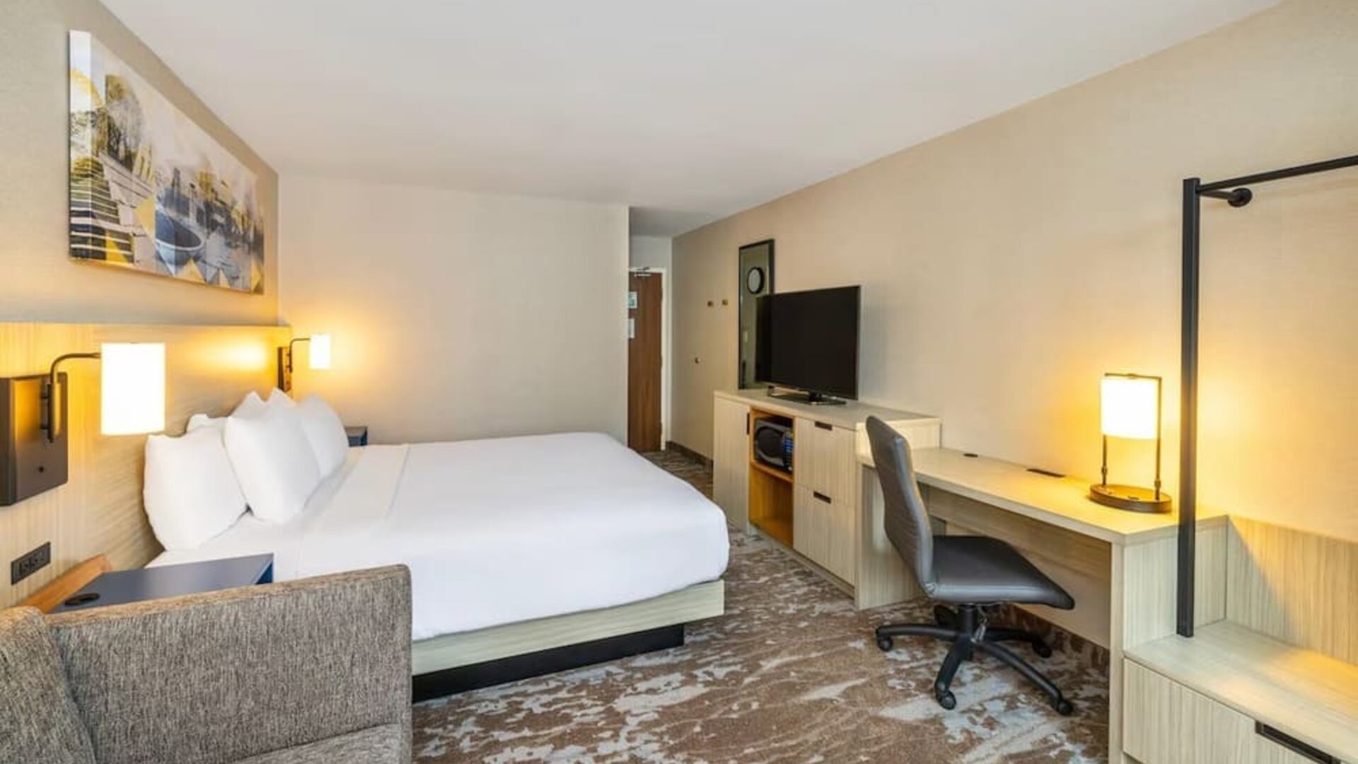 Spacious guest room with king bed, sofa, work desk, and modern amenities at Comfort Inn Sydney.