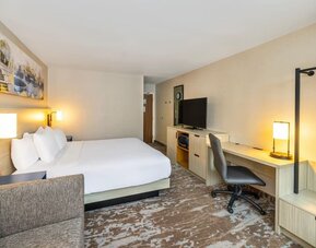Spacious guest room with king bed, sofa, work desk, and modern amenities at Comfort Inn Sydney.