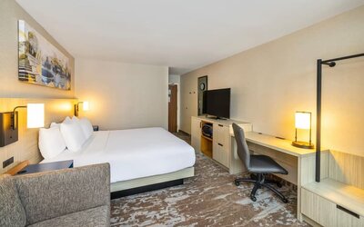 Spacious guest room with king bed, sofa, work desk, and modern amenities at Comfort Inn Sydney.