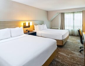Comfortable guest room with two queen beds, work desk, and large windows for a relaxing stay at Comfort Inn Sydney.