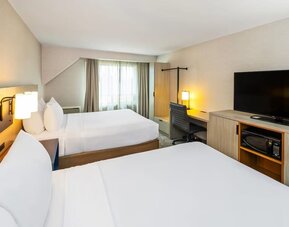 Spacious guest room with two queen beds, flat-screen TV, work desk, microwave, and mini fridge at Comfort Inn Amherst.