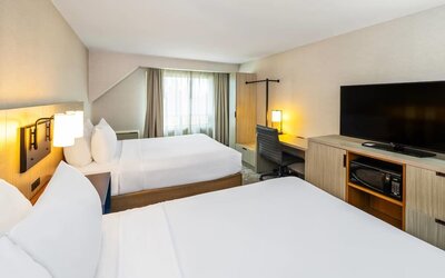 Spacious guest room with two queen beds, flat-screen TV, work desk, microwave, and mini fridge at Comfort Inn Amherst.