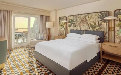 Stylish king guest room featuring plush bedding, private balcony, comfortable seating, and coastal-inspired décor at Hyatt Centric Delfina Santa Monica.