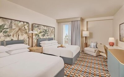 Bright guest room with two comfortable beds, private balcony, ergonomic workspace, and contemporary coastal-inspired furnishings at Hyatt Centric Delfina Santa Monica.