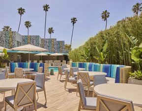 Outdoor poolside patio with comfortable seating, dining tables, and relaxing spaces to enjoy the Southern California sunshine at Hyatt Centric Delfina Santa Monica.