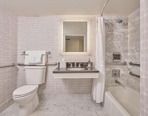 Accessible guest bathroom featuring a roll-in shower, grab bars, spacious layout, and modern vanity at Hyatt Centric Delfina Santa Monica.