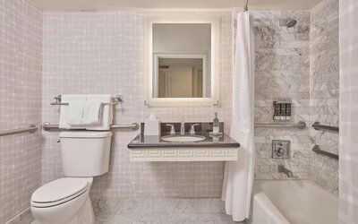 Accessible guest bathroom featuring a roll-in shower, grab bars, spacious layout, and modern vanity at Hyatt Centric Delfina Santa Monica.