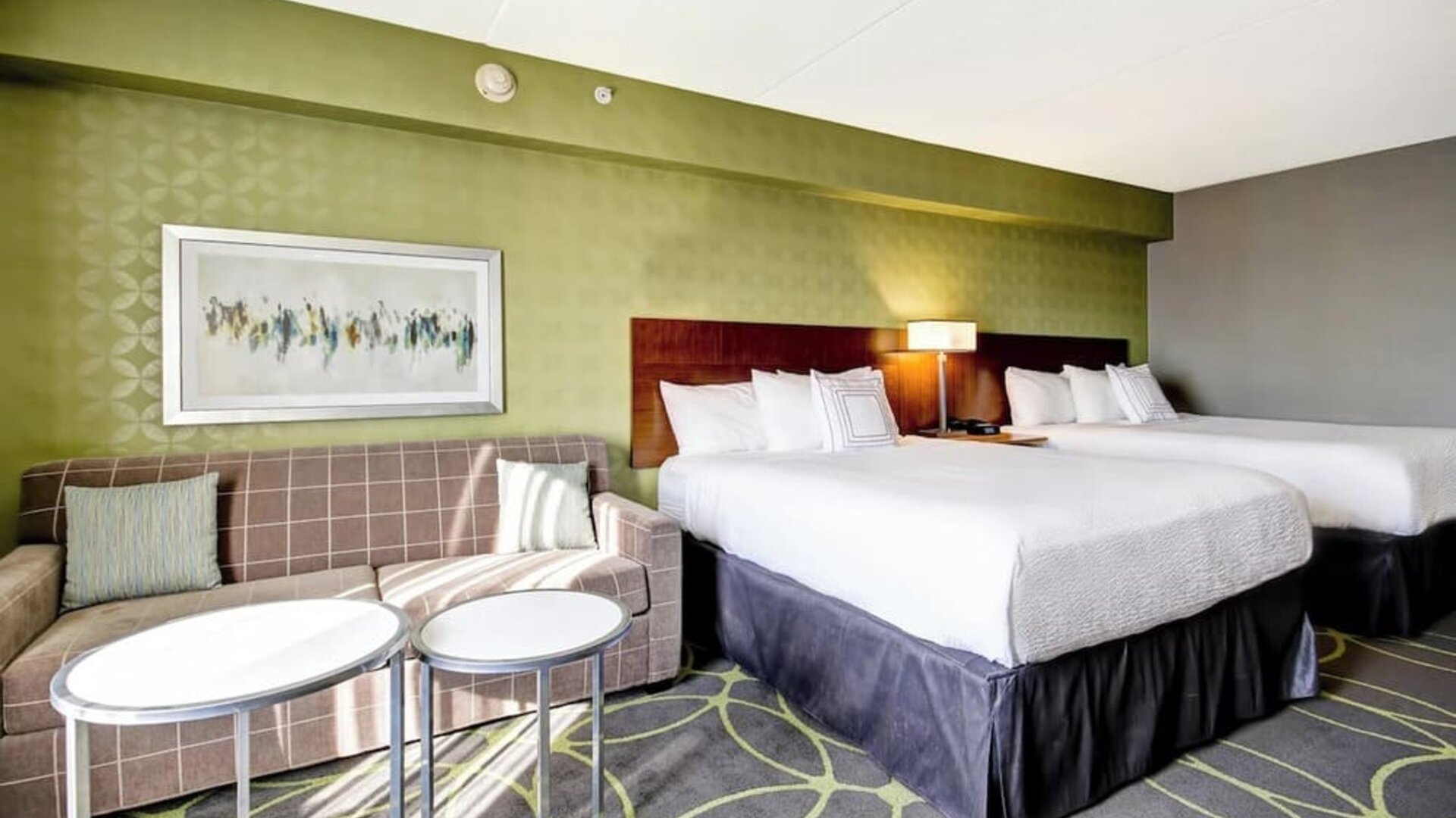 Comfortable guest room featuring two queen beds, a sofa, and modern décor at Fairfield Inn & Suites Guelph.