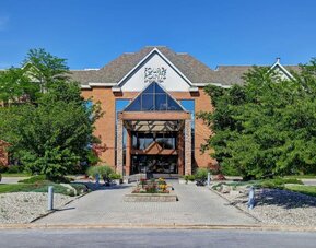 Welcoming hotel entrance surrounded by landscaped gardens at Four Points by Sheraton St. Catharines Niagara Suites.