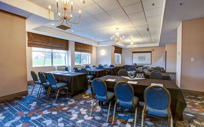 Flexible meeting room with banquet-style seating, presentation screen, and natural light at Four Points by Sheraton St. Catharines Niagara Suites.