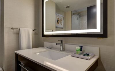 Modern guest bathroom featuring a sleek vanity with illuminated mirror and premium bath amenities at Four Points by Sheraton St. Catharines Niagara Suites.