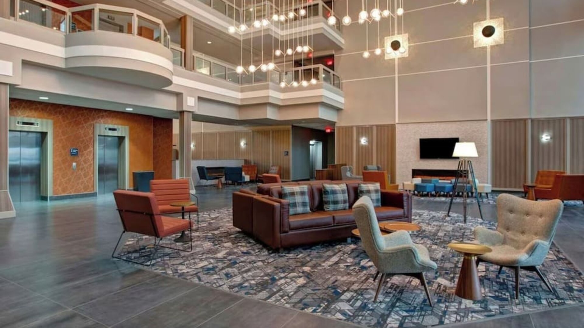 Bright atrium lobby with contemporary seating areas and elegant lighting at Four Points by Sheraton St. Catharines Niagara Suites.