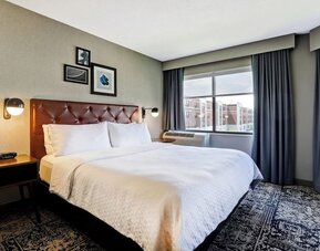 Contemporary king guest room featuring plush bedding, large windows, and modern décor at Four Points by Sheraton St. Catharines Niagara Suites.