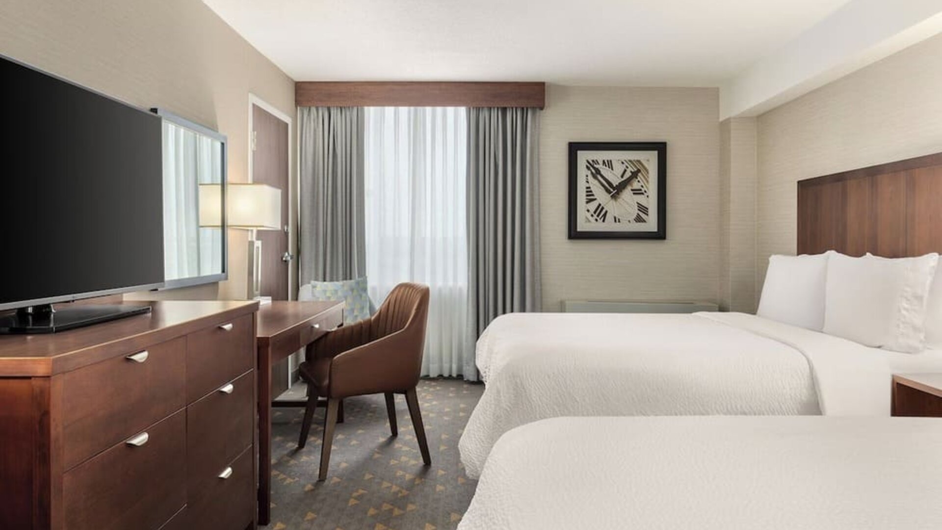 Comfortable guest room with two beds, dedicated workspace, and modern amenities at Holiday Inn Oakville Centre.