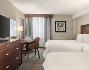 Comfortable guest room with two beds, dedicated workspace, and modern amenities at Holiday Inn Oakville Centre.