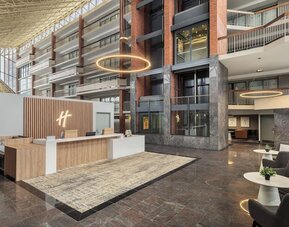 Modern reception area with welcoming front desk and spacious atrium lobby at Holiday Inn Oakville Centre.