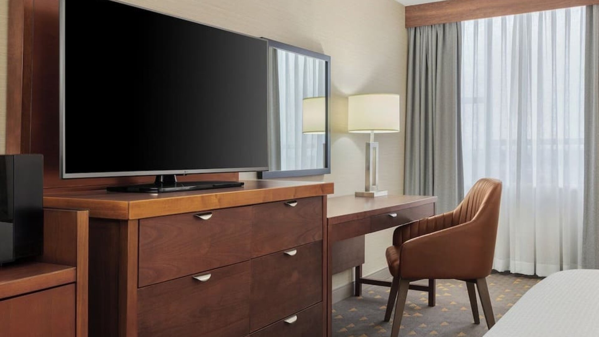 In-room workspace with writing desk, flat-screen TV, and functional storage designed for business and leisure travelers at Holiday Inn Oakville Centre.
