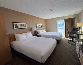 Double queen guest room with two comfortable beds, dedicated workspace, flat-screen TV, and large window at Comfort Inn Baie-Comeau.