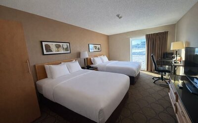 Double queen guest room with two comfortable beds, dedicated workspace, flat-screen TV, and large window at Comfort Inn Baie-Comeau.