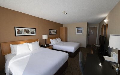 Spacious double queen guest room with premium bedding, work desk, flat-screen TV, and comfortable accommodations at Comfort Inn Baie-Comeau.