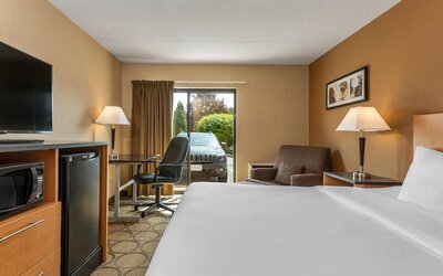 Guest room with a king bed, ergonomic workspace, mini refrigerator, HDTV, and comfortable seating area at Comfort Inn Sherbrooke.