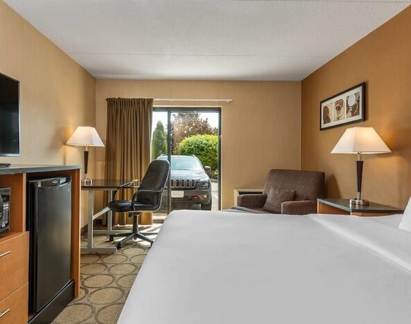 Guest room with a king bed, ergonomic workspace, mini refrigerator, HDTV, and comfortable seating area at Comfort Inn Sherbrooke.