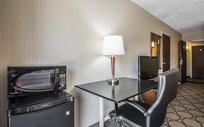 In-room workspace featuring a desk, ergonomic chair, microwave, mini refrigerator, and coffee service at Comfort Inn Sherbrooke.
