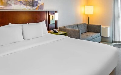 King guest room featuring plush bedding, a cozy loveseat, and modern furnishings at Comfort Inn Sudbury East.