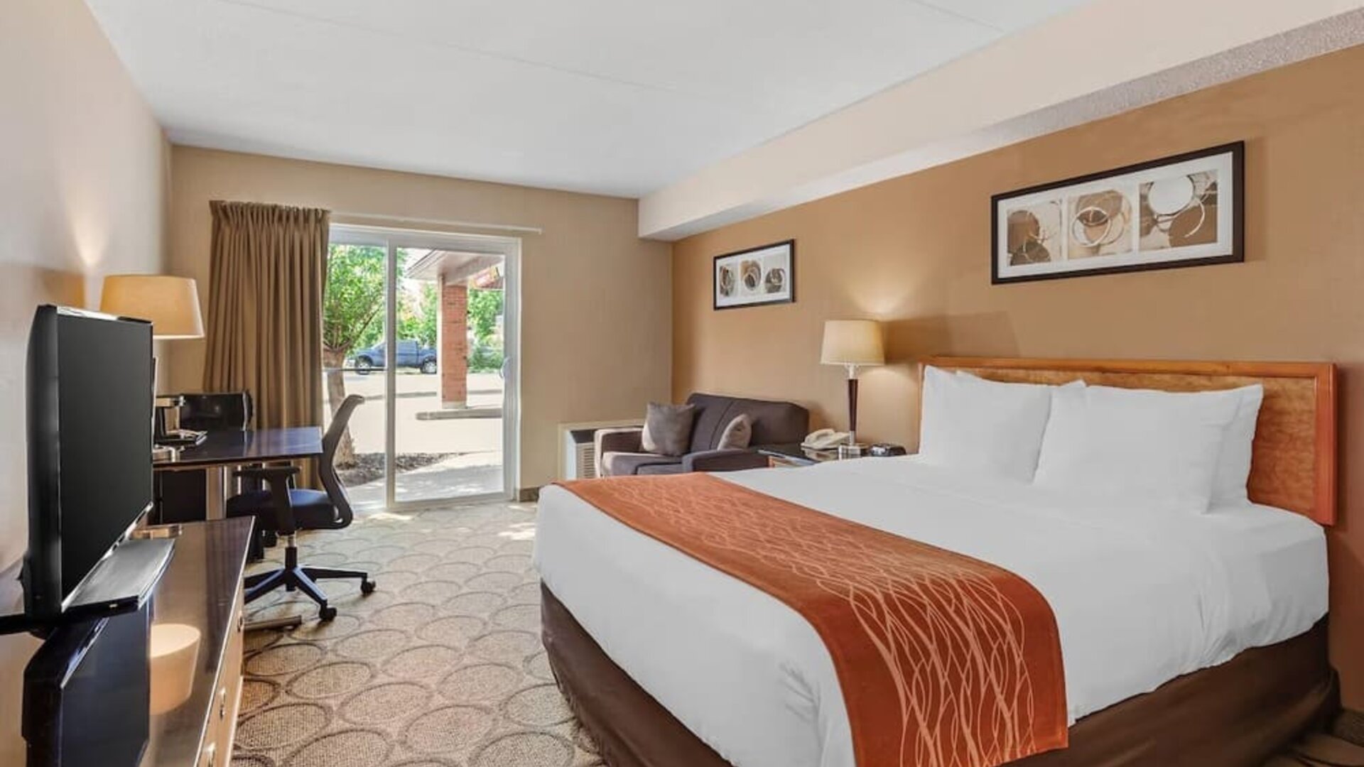 Spacious guest room with a king bed, sofa, and work desk at Comfort Inn Brantford.