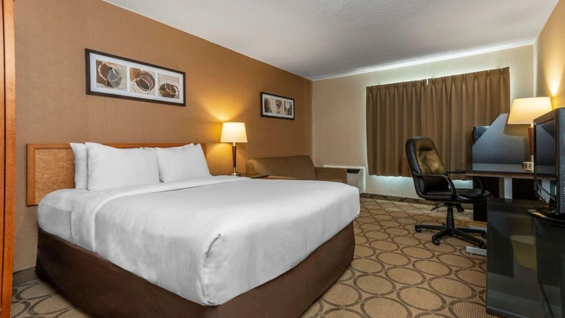 Spacious king guest room with a work desk and seating area at Comfort Inn Sept-Iles.
