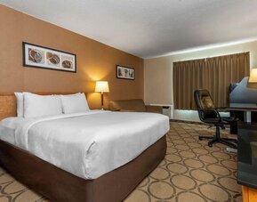 Spacious king guest room with a work desk and seating area at Comfort Inn Sept-Iles.