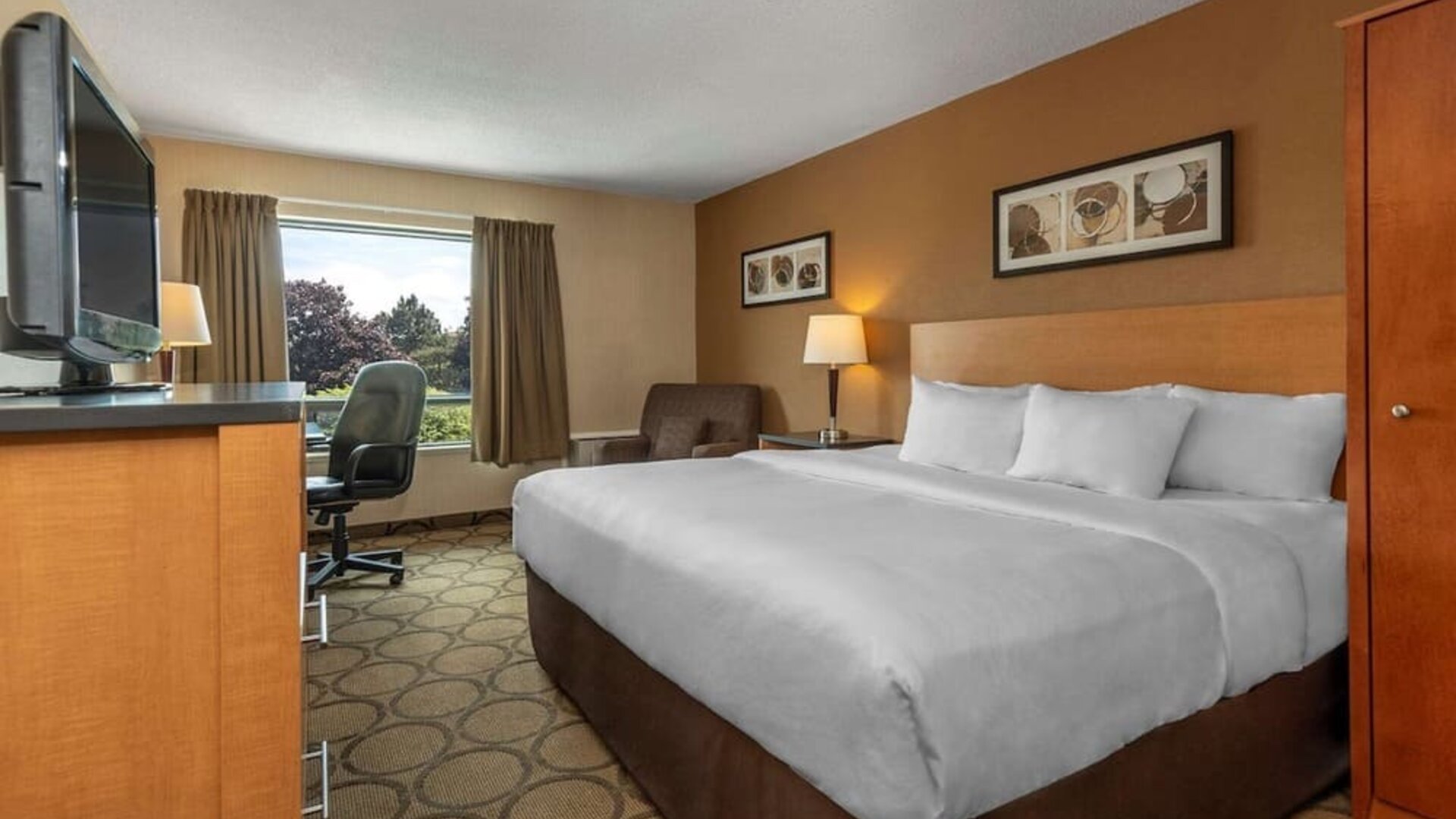 King guest room with natural light and seating area at Comfort Inn Sept-Iles.
