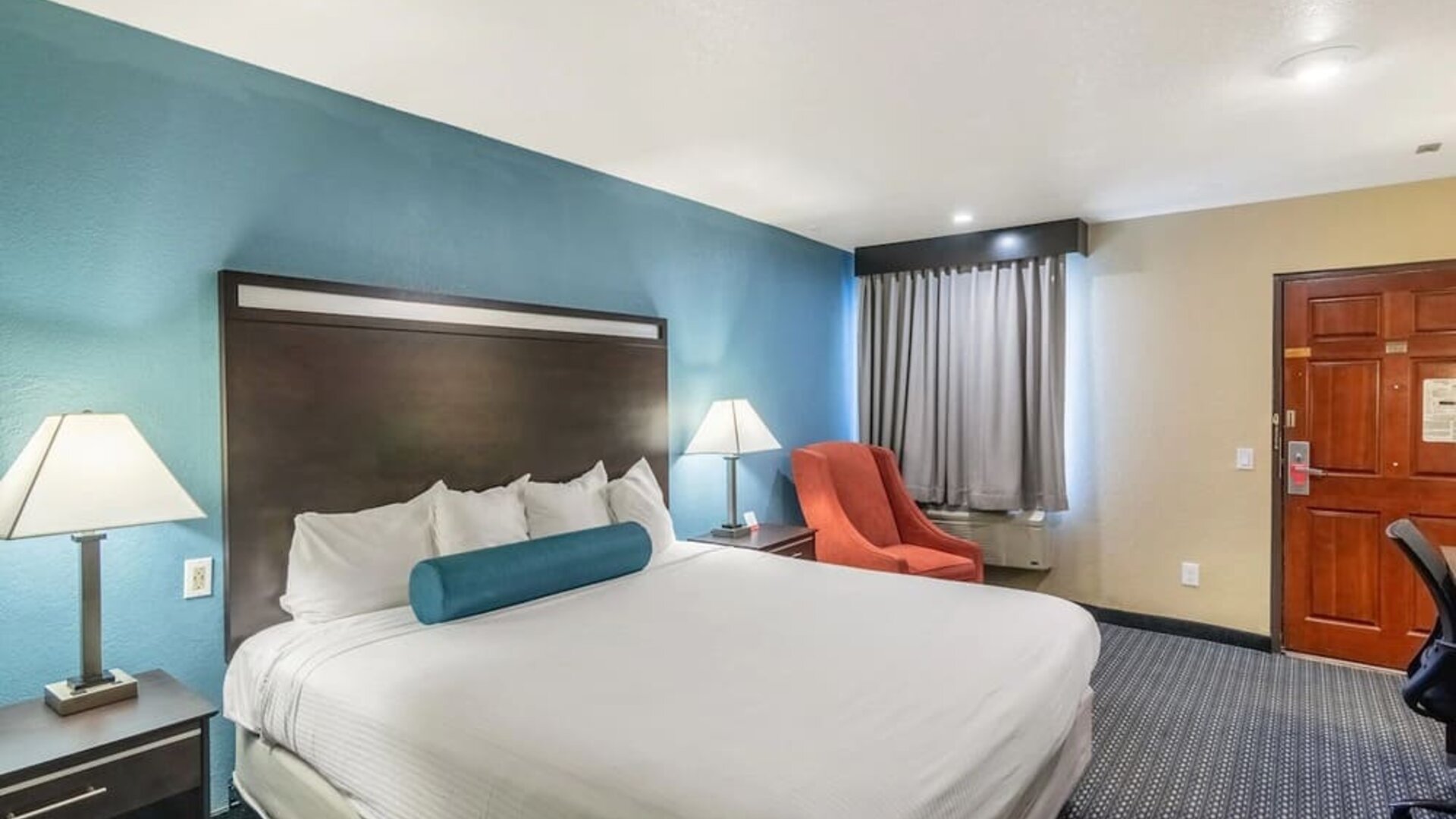 Spacious guest room with a king bed and armchair at Glenridge Inn Glendale Pasadena.