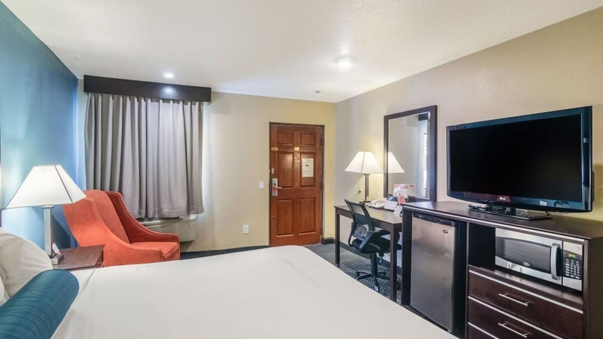 Guest room with a king bed, TV, work desk, and seating area at Glenridge Inn Glendale Pasadena.