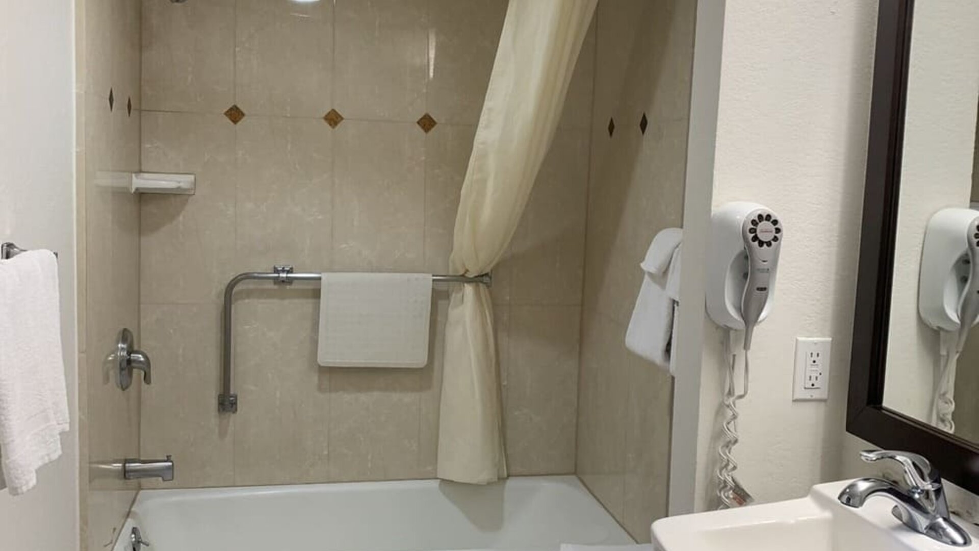 Accessible guest bathroom with a bathtub and shower at Glenridge Inn Glendale Pasadena.