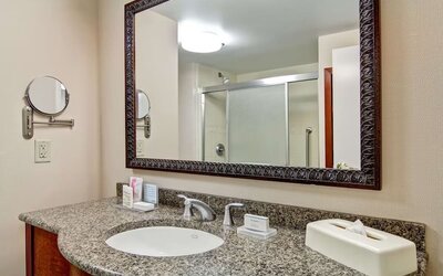 Guest bathroom with a granite vanity and walk-in shower at Hampton Inn & Suites By Hilton Guelph.