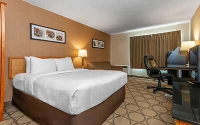 Guest room with a king bed, armchair, and work desk at Comfort Inn Regina.
