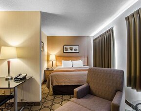 Guest room with a king bed, sofa, and workspace at Comfort Inn Regina.