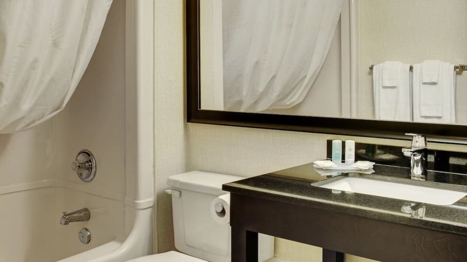 Guest bathroom with a bathtub, vanity, and large mirror at Comfort Inn Brandon.