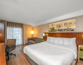 King guest room with a sofa, work desk, and natural light at Comfort Inn Winnipeg Airport.