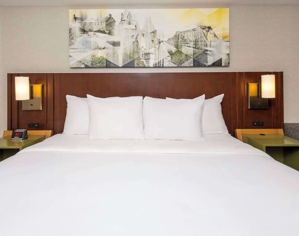 King bed with upholstered headboard and bedside lighting at Comfort Inn Brossard.