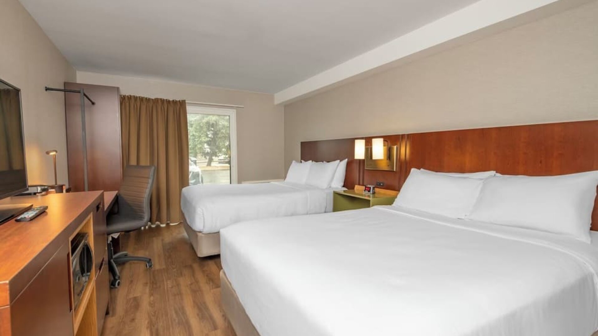 Guest room with two queen beds, TV, and work desk at Comfort Inn Brossard.